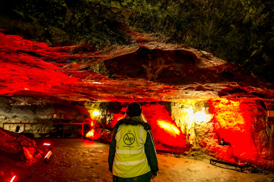 Person in AND high vis looking into dark cave.